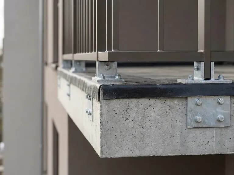 Modern bir apartman balkonunun yapısal detayları; beton kenar, su yalıtım, metal korkuluk.